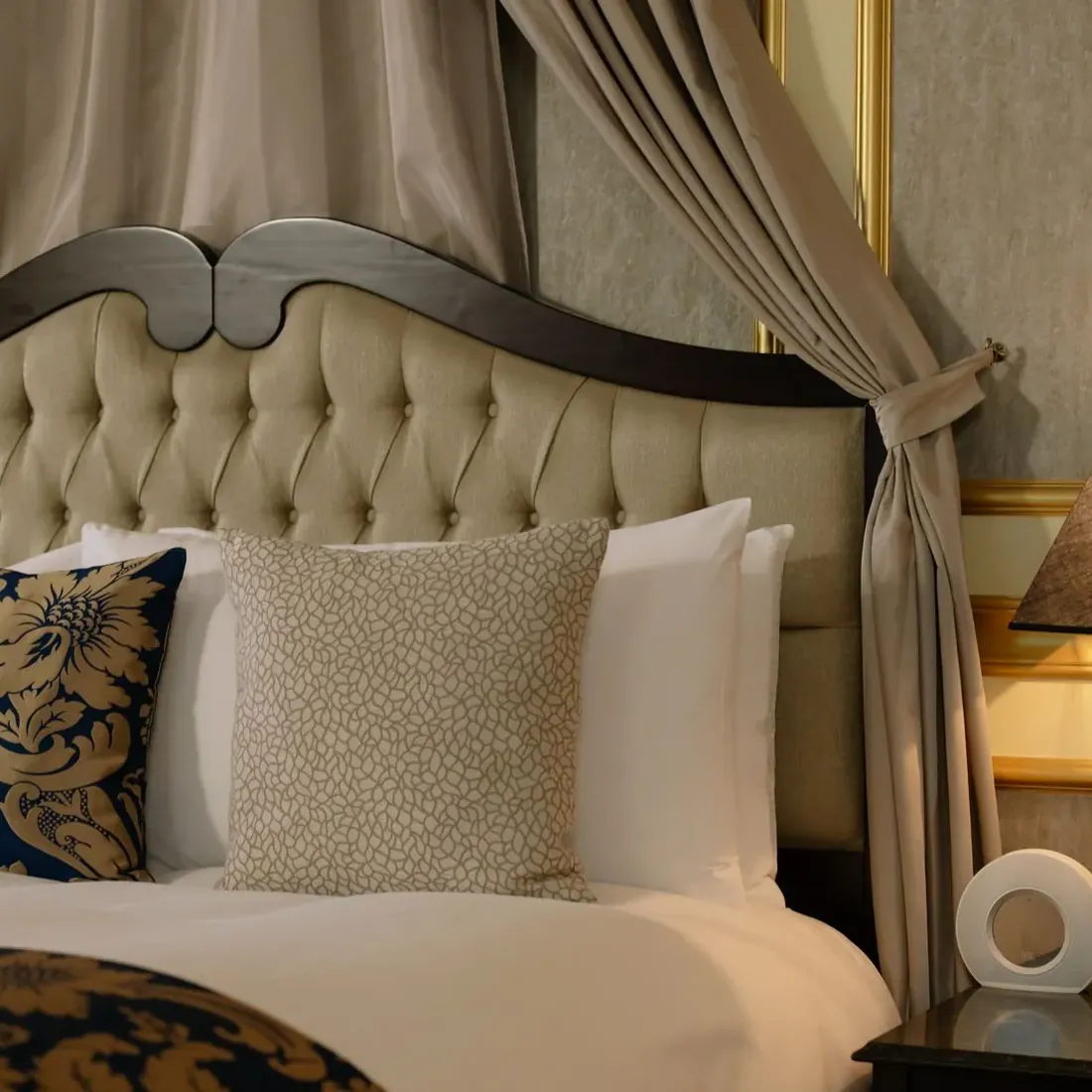 Bedroom with a tufted headboard, linen bedding and warm lamps