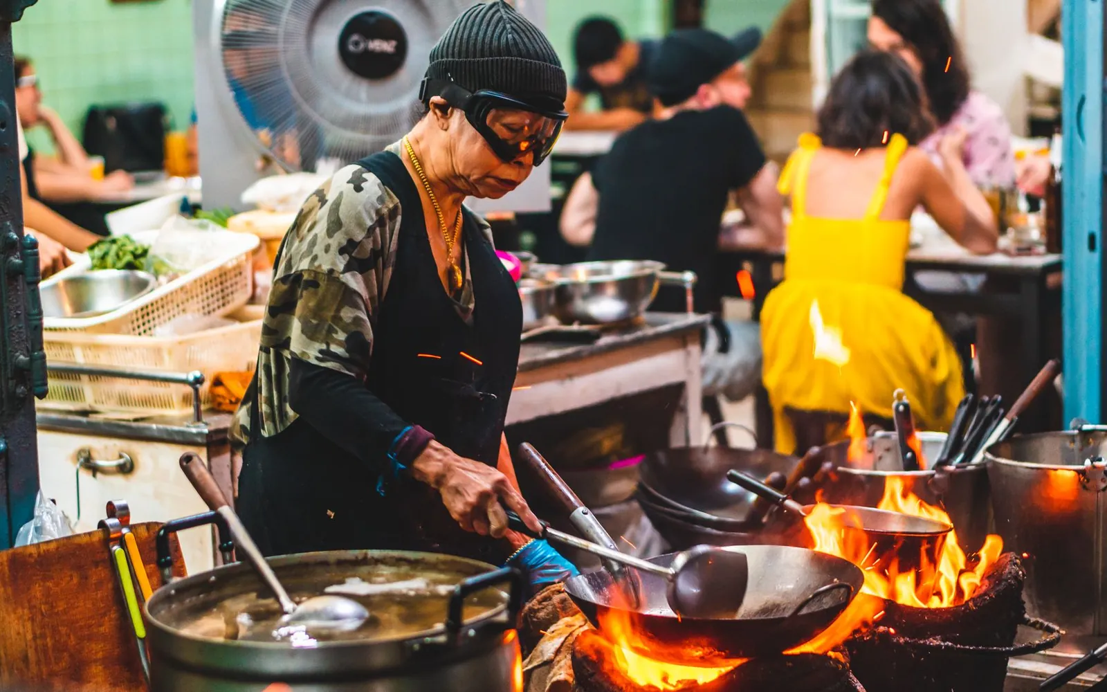 A cook working a wok over a high flame