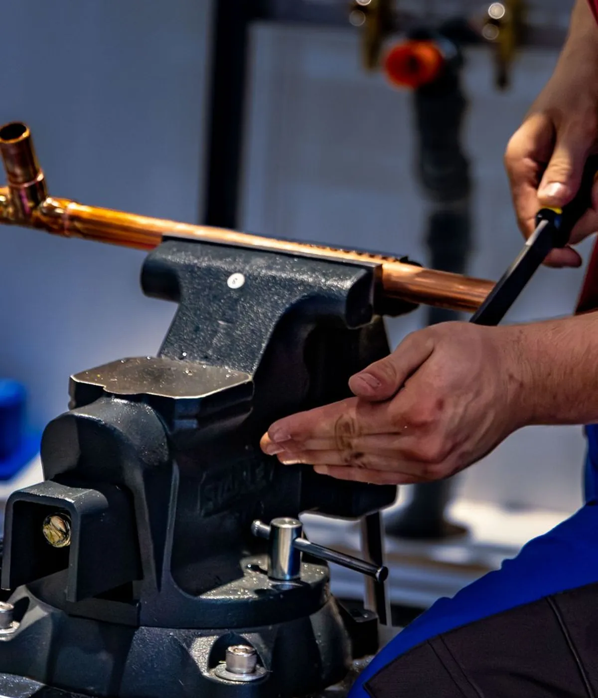 A Pipewright plumber cutting a copper pipe held in a bench vice