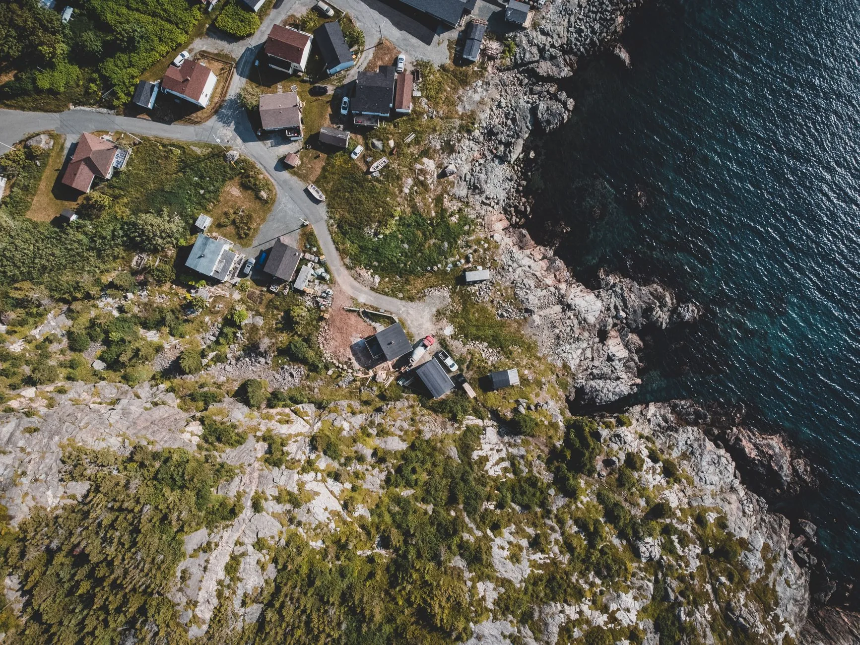 A modern glass house on a rocky coastline seen from above