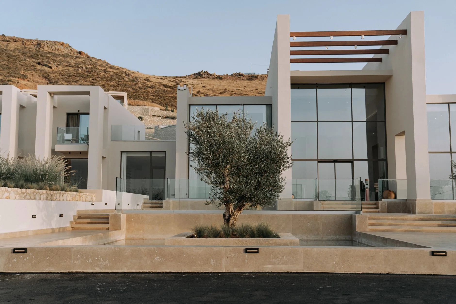 A minimalist glass pavilion standing alone in an open desert at sunset