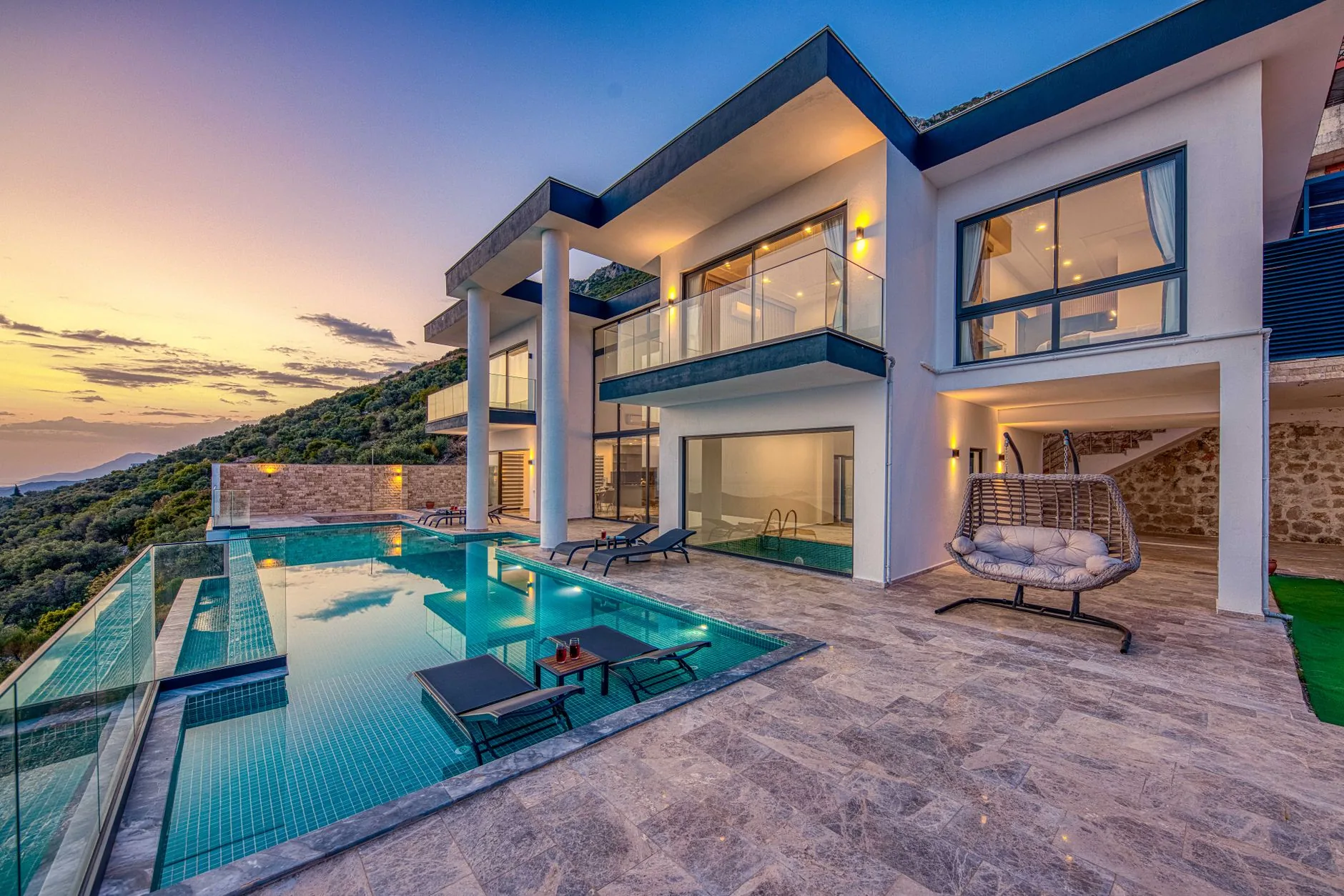 A glass-walled villa mirrored in a still reflecting pool at twilight